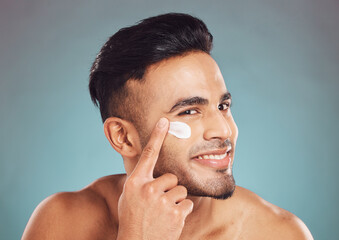 Poster - Man, cosmetics and face cream with smile in studio for test, product or moisturizer by blue background. Person, model and happy with serum application, skincare and dermatology for facial aesthetic