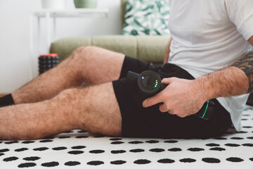 Man using a machine to massage his muscles at home