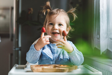 The baby is trying a new taste of solid food. Eating healthy food from the beginning is important. Young child doesn't want to eat vegetable and fruit.