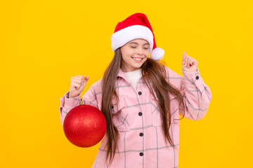 Wall Mural - cheerful child in santa claus hat hold christmas decorative ball on yellow background, santa