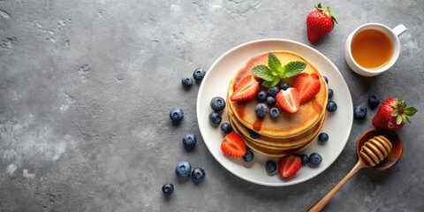 Wall Mural - Top view of delicious pancakes with blueberries, strawberries, and honey on a grey concrete table background , sweet, breakfast