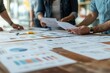 © ImagePulse - Small business owners gathered around a table with printed marketing plans, sharing ideas and strategies, marketing strategy, collaborative effort