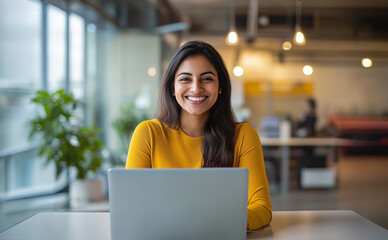 pretty young south asian woman working on her laptop, young professional wearing yellow in a modern 