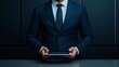 © Oatkhaphon - A professional man in a suit holding a tablet, symbolizing business and technology in a modern office environment.