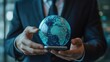 © ShinneProject - A businessman holds a smartphone with a glowing, holographic earth globe.