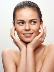 Wall Mural - Gorgeous young woman embracing her beauty while posing with her hands on her face and looking directly at the camera