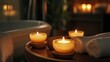 © Tcukimay - Three lit candles on a wooden tray with a white towel in a bathroom setting.