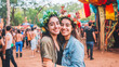 © Adrenaloby - Two smiling women at outdoor festival with floral crowns, celebrating friendship and summer joy