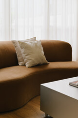 Aufkleber - A modern brown sofa with two decorative pillows sits elegantly in bright room, complemented by sleek coffee table. soft textures and warm tones create cozy atmosphere