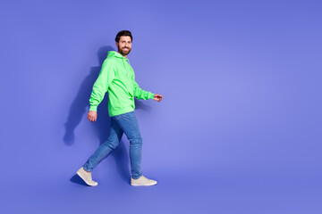 Poster - Full length photo of handsome young guy walk profile empty space dressed stylish green garment isolated on violet color background