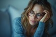 © Сергей Белый - The beautiful woman with glasses is looking down, rubbing her tired and achy eyes while feeling exhausted.