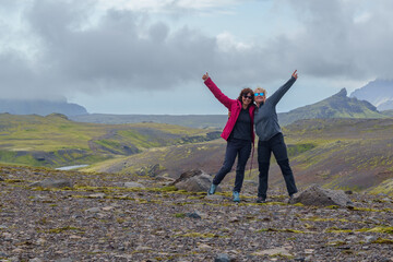 Two women celebrating on rocky landscape with mountain view