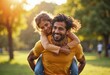 © PhotoPhantom - Playful Indian father giving piggyback ride to his child, sharing a joyful moment of togetherness and family bonding in the park, both smiling and enj