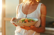 © Spicy World - A woman enjoys a colorful bowl of fresh salad during sunset in a cozy kitchen