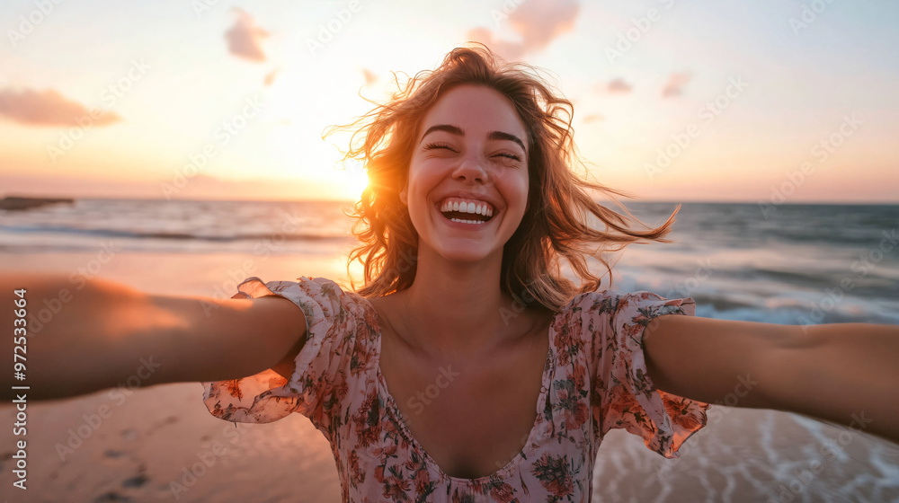 Young woman laughing joyfully on the beach at sunset, taking a selfie ...