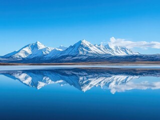 Sticker - A serene landscape featuring snow-capped mountains reflecting in a calm lake under a blue sky.