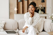 © Maria Vitkovska - Beautiful young woman sitting on sofa with laptop thinking about future opportunities