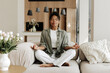 © Maria Vitkovska - Young woman meditating sitting in lotus pose on sofa at home