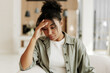 © Maria Vitkovska - Young black woman feeling sad and touching her head at home