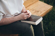 © ADDICTIVE STOCK - Man reading Bible outdoors on a wooden bench