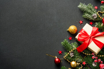 Wall Mural - Christmas flat lay background. Present box, fir tree and holiday decorations on black.