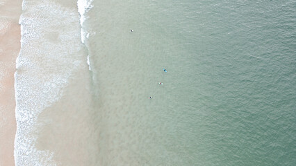     Surfers catching waves, waiting for a wave to come in the middle of the ocean near the beach during a beautiful day