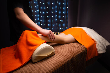 Wall Mural - Professional massage therapist gives a calf muscle massage to a young female patient