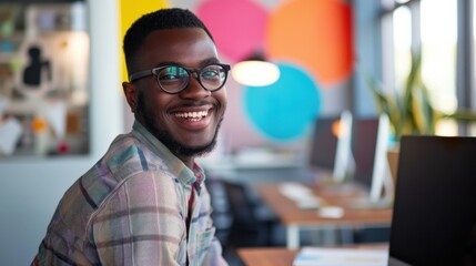 Fototapete - A smiling man wearing glasses is sitting at a desk in front of a colorful wall