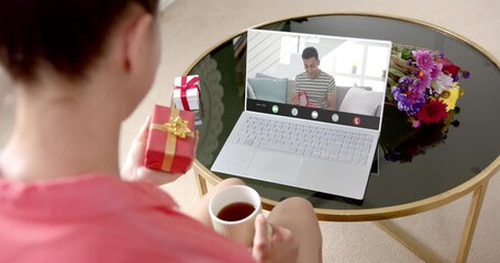 Canvas Print - Caucasian woman holding red gift using laptop with biracial man on screen