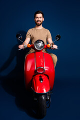 Canvas Print - Vertical photo of chilling young man in beige t shirt likes riding rental scooter moped isolated on dark blue color background