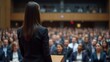 © GMeta - Confident businesswoman in black blazer speaks at podium to audience in modern conference hall