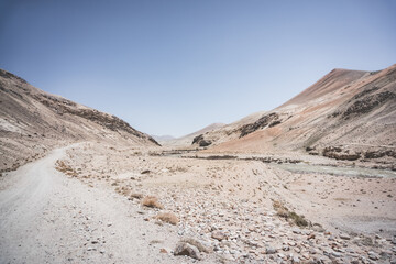 Sticker - Dusty road of the Pamir Highway winds and twists in the valley of the Tien Shan Mountains in Tajikistan in the Pamirs, landscape for the background