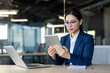 © Liubomir - Asian businesswoman engages with a tablet in office setting. Scene highlights technology use in workplace, with open laptop and notepad nearby, emphasizing productivity and modern business practices