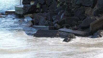 Wall Mural - Waves breaking against rocks and concrete slabs