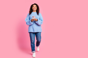 Full body portrait of nice young girl hold phone walk empty space isolated on pink color background