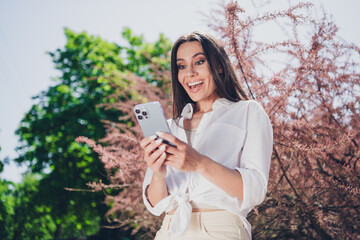 Poster - Photo of attractive young cheerful girl hold device excited wear white garment having fun outside outdoors