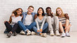 © Prostock-studio - Multiracial happy students posing over white brick wall, sitting on floor and embracing, friendship concept