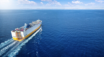 Aerial view of a large car RORO transporter ship sailing with speed over the ocean as a concept for the transport industry