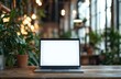 © Art_You - Mockup of a blank empty laptop screen on a wooden desk surrounded by green plants in a modern office setting