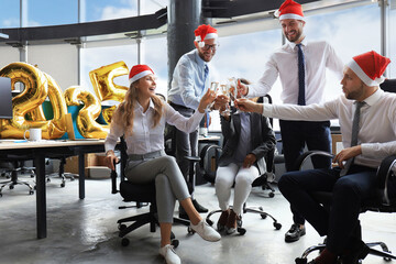 Wall Mural - Business people are celebrating holiday in modern office drinking champagne and having fun in coworking. Merry Christmas and Happy New Year 2025.