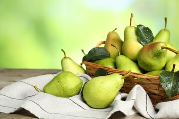 Canvas Print - Fresh pears and leaves with water drops on wooden table against blurred green background, closeup. Space for text