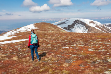 Wall Mural - Hiker woman on scenic hiking trail over snow covered alpine meadows and rolling hills to snow-capped mountain peak Lenzmoarkogel, Gleinalpe, Lavantal Alps, Styria, Austria. Wanderlust in Austrian Alps