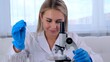 © Евгения Медведева - Young scientist laboratory assistant looks through a microscope in the laboratory. A young scientist is doing some research.