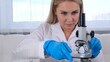 © Евгения Медведева - Female scientist laboratory assistant looks at a petri dish with genetically modified samples of chemicals under a microscope. Microbiologist works in a modern laboratory with technological equipment.