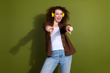 Portrait of nice young girl headphones point fingers you wear brown shirt isolated on khaki color background