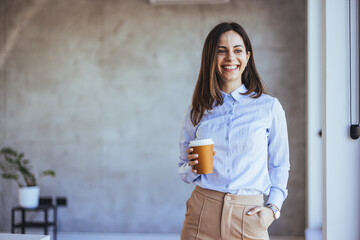 Confident Woman Smiling with Coffee in Modern Office