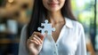 © arthit - Businesswoman holding a puzzle piece, symbolizing the solution to a business challenge.