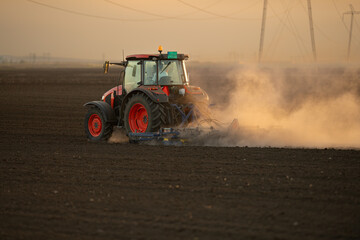 Wall Mural - A red tractor prepares the land with a plow.