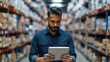 © Vilaysack - Warehouse manager in a large storage facility, using a digital tablet to check inventory. Shelves filled with boxes line the background, highlighting a busy and organized storage environment.