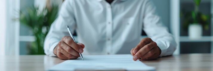 Wall Mural - Businessman in a light blue shirt carefully reviewing paperwork while holding a pen, focusing on details in a modern office setting